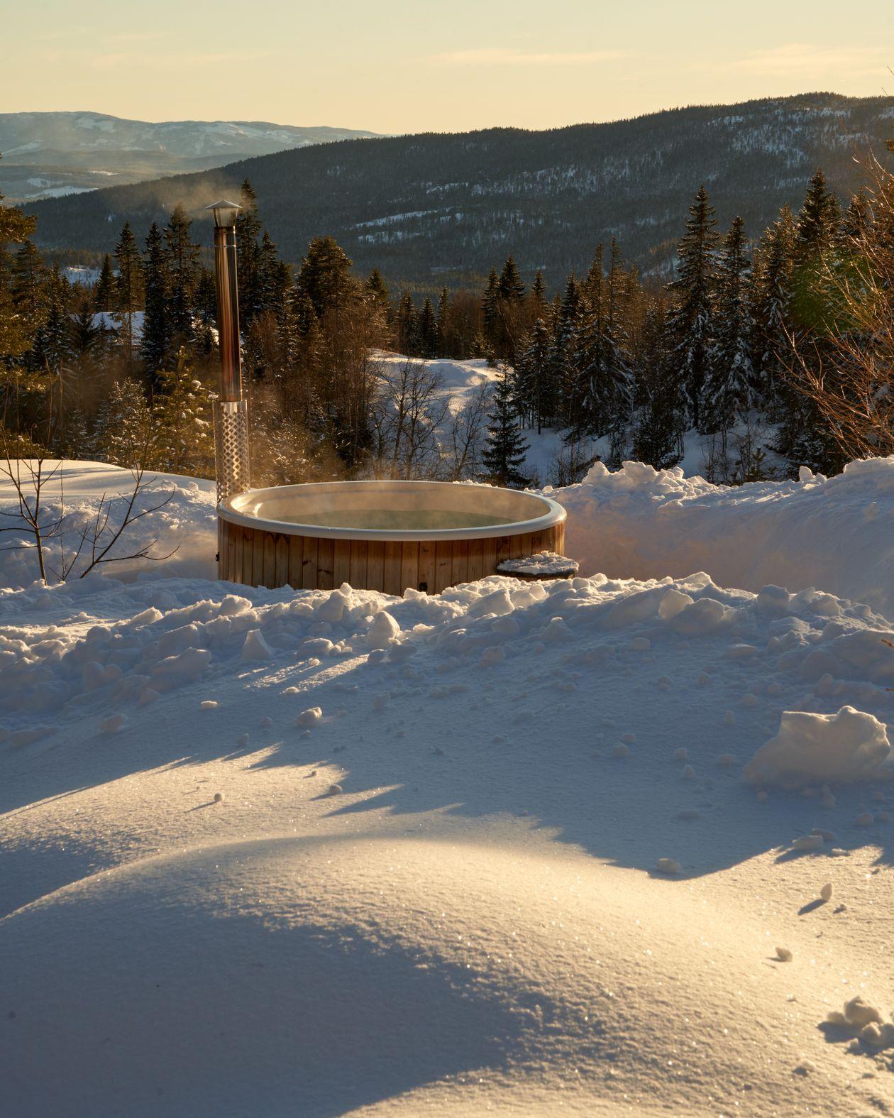 Banheira de hidromassagem aquecida ao ar livre cercada de neve em resort de montanha
