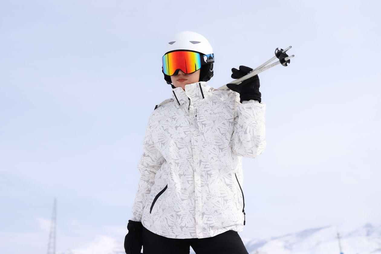 Esquiador com jaqueta impermeável e óculos de neve em pista de esqui
