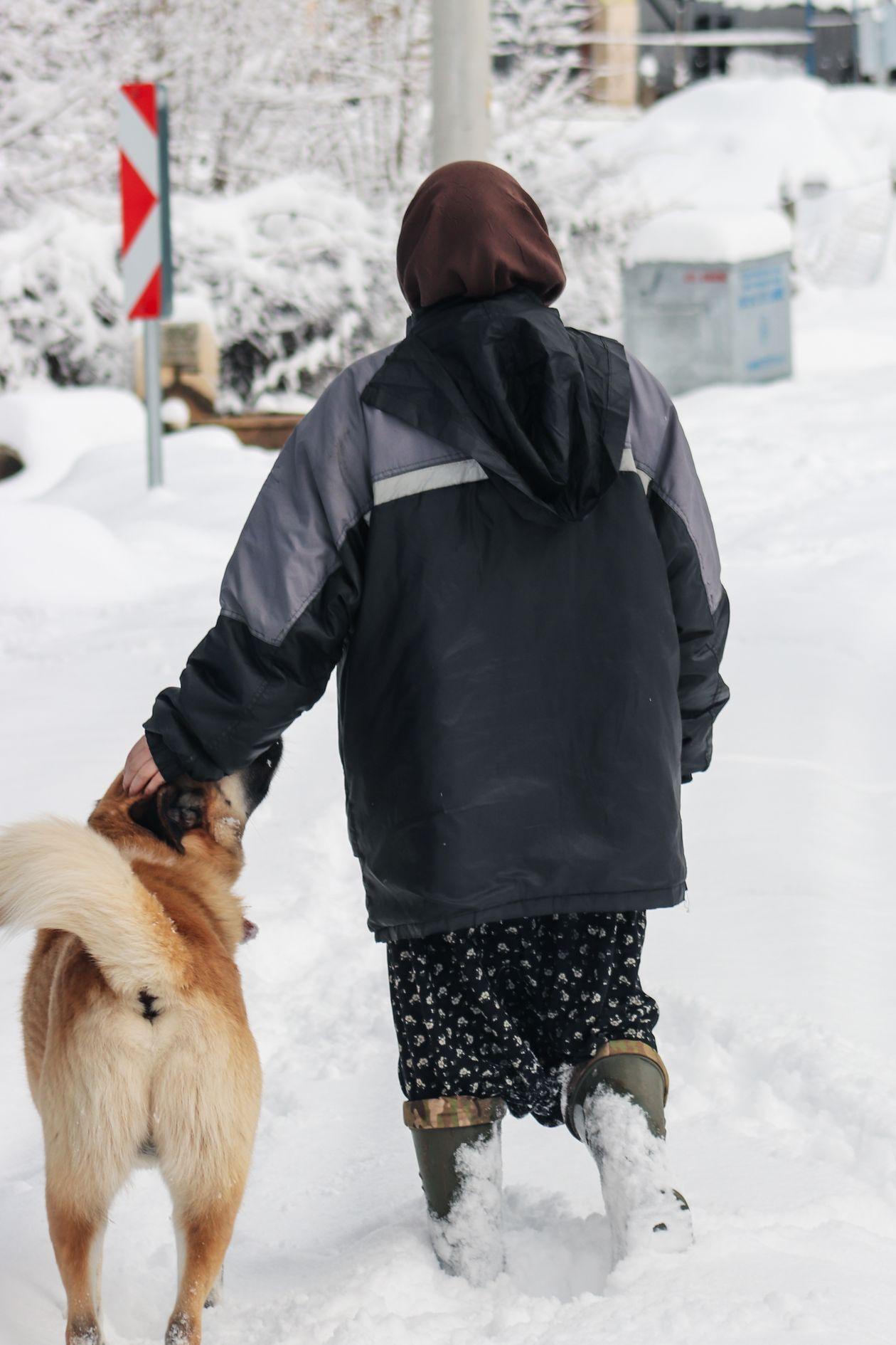 Pessoa caminhando com botas antiderrapantes em rua coberta de neve