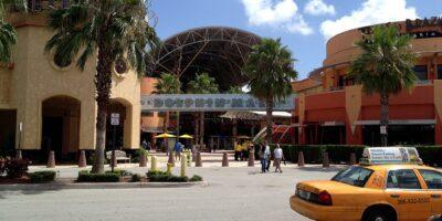 Entrada do Dolphin Mall, em Miami, com palmeiras e um táxi amarelo